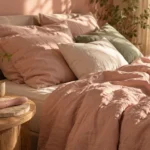 Unmade bed with blush linen and soft pillows in morning light