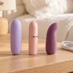 Three compact bullet vibrators in lilac, blush and plum on a pale table.