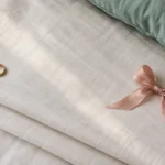 Gold ring and a pink ribbon bow on a folded white bedsheet