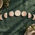 White ceramic discs arranged as moon phases on dark green cloth