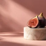 Halved fig on a marble pedestal against a blush backdrop