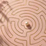 Gold-line maze on blush paper with a pearl near the centre